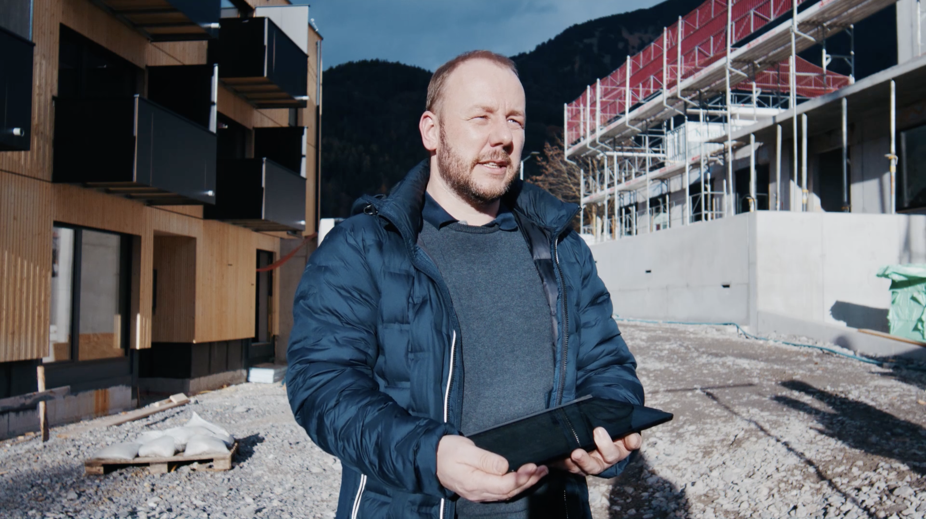 Josef Feuerstein hält ein IPad auf einer Baustelle