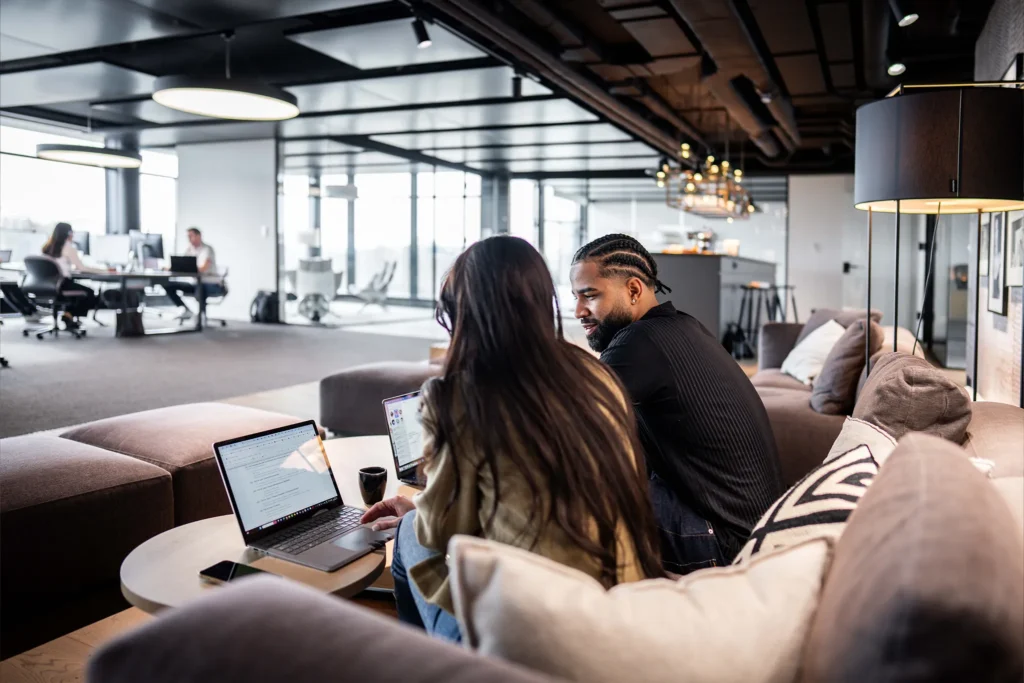 Zwei Personen im Büro, die gemeinsam auf einen Laptop schauen – symbolisiert Teamarbeit und die Nutzung von CoffeeNet 365 für effiziente Zusammenarbeit