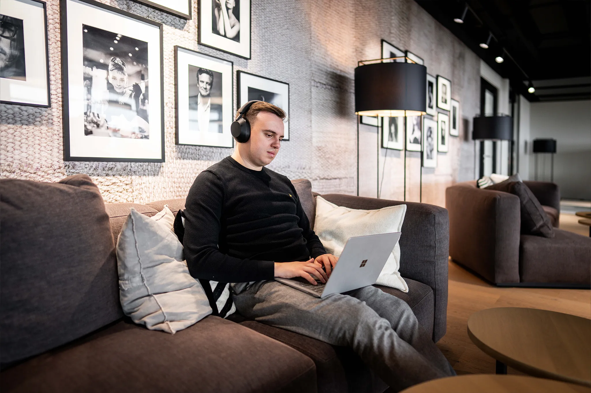 Eine Person sitzt auf einem Sofa und führt mit einem Laptop ein Meeting – zeigt die Flexibilität und Effizienz der Meeting App von CoffeeNet 365.