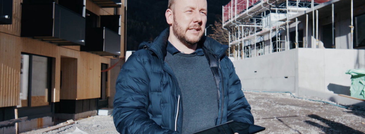 Josef Feuerstein hält ein IPad auf einer Baustelle